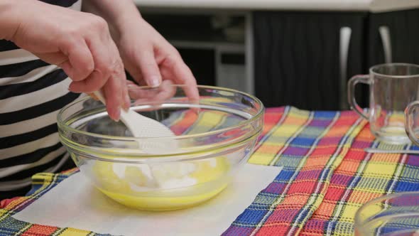 Senior Caucasian Woman Mixing Sugar and Liquid Dough in the Bowl with White Plastic Spatula