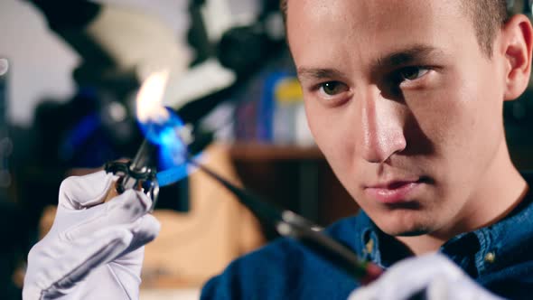 Jeweler Uses Burner To Heat a Ring. A Goldsmith in Jewelry Working with Ring. alt