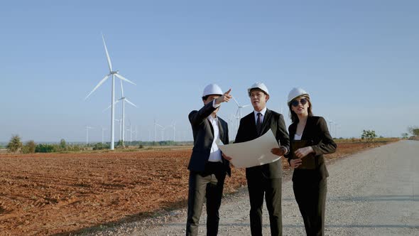 inspector and an engineer with a secretary are inspecting a project in a wind turbine field