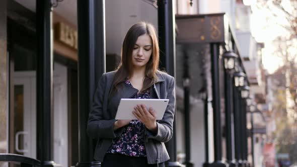 Portrait of the Beautiful Young Businesswoman Which Use the Tablet Device on the Street in the alt