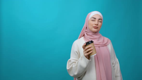 Calm Beautiful Young Muslim Woman in Hijab Hold Cup of Coffee or Tea Drink