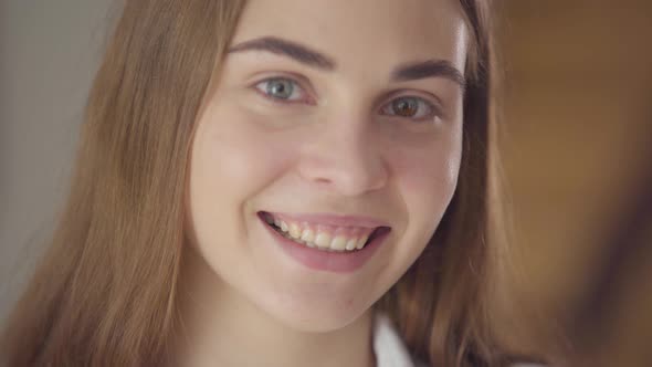 Close-up Portrait of Beautiful Young Smiling Woman with Different Colored Eyes Looking at Camera alt
