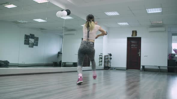 Caucasian female dancer choreographer performing hiphop animation in a dance studio against the mirr alt