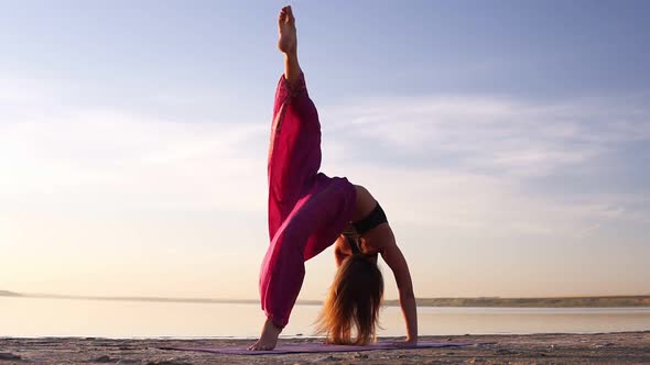 Close Up View of a Young Woman in Pink Yogi Pants Practicing on Sand Near the Sea or Lake in the alt