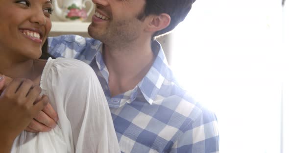 Happy young couple embracing each other in kitchen alt