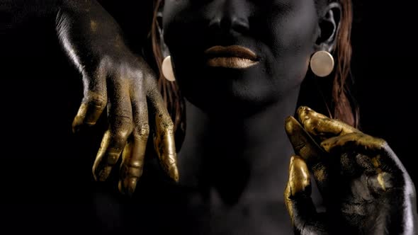 Art Portrait of a Young Female Model with Black Skin, Golden Lips, Hands, Eyes. alt
