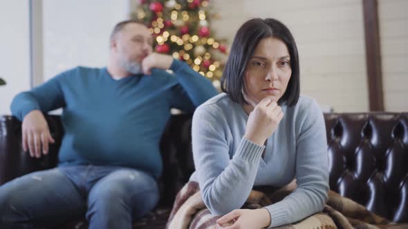 Beautiful Caucasian Upset Woman Looking Back at Blurred Man and Holding Head with Hands. Portrait of alt