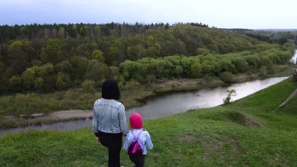 Mother and daughter enjoys the view on the coast Sluch river hills