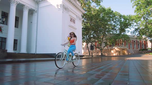 Young Attractive Woman in Hat Riding on Vintage Bike in City Center and Having Some Fun alt