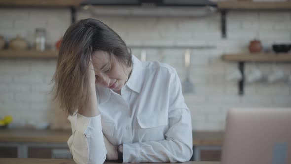 Depressed Young Slim Woman Crying Sitting in Kitchen at Home alt