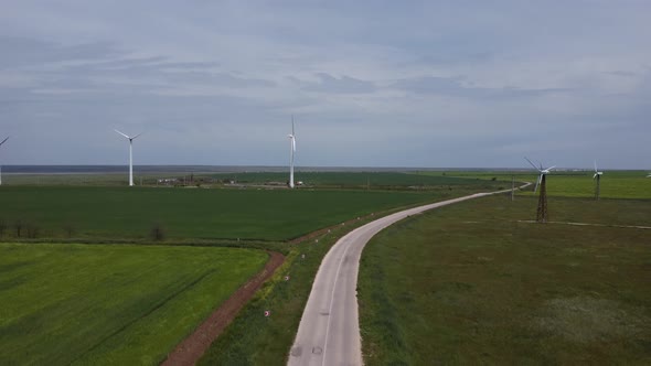 White Wind Farms Stand in the Middle of Green Fields in Clear Weather