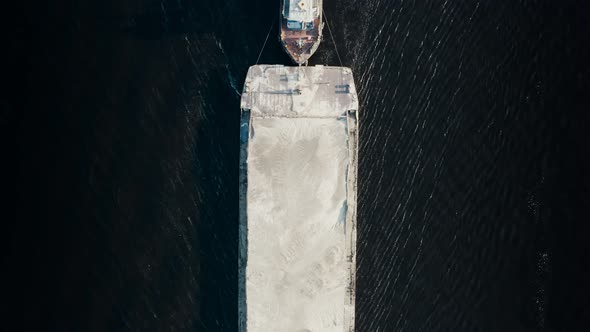 Top Aerial View of Tugboat Towing Large Barge to Industrial Port alt