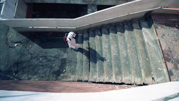 Person in Hazmat Sanitizes Stairs on a Street alt