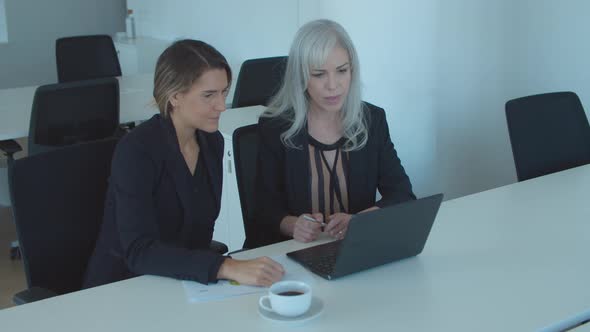 Two Serious Business Ladies Using Laptop for Video Talk alt