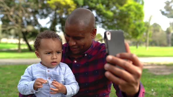African American Bald Father Trying To Make Selfie with Cute Son alt