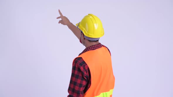 Rear View of Young Hispanic Man Construction Worker Directing and Pointing Finger
