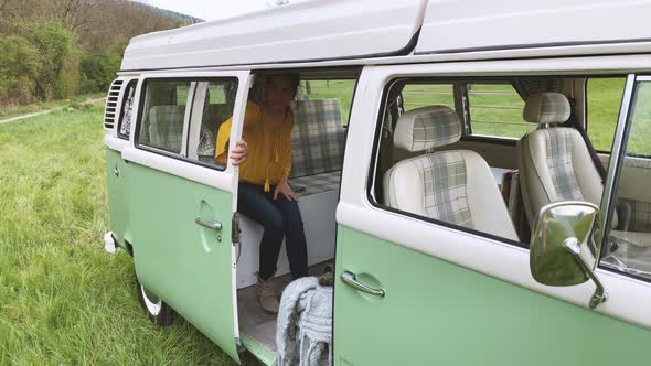 Young woman open the door of a camper