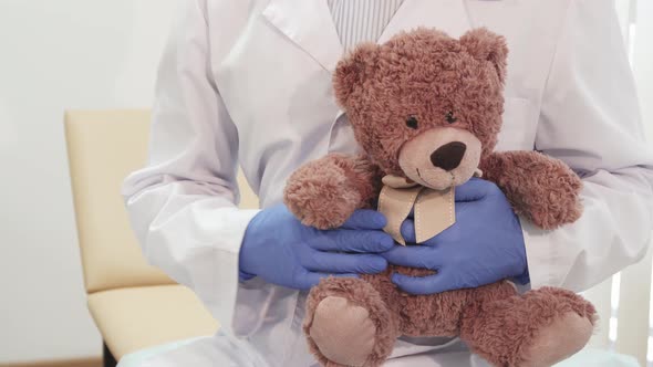 The Professional Doctor Holds a Teddy Bear and Shows Thumbs Up alt