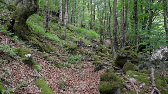 Tourist Man Hiker with Backpack Walking in Mountains Forest with Rocks alt