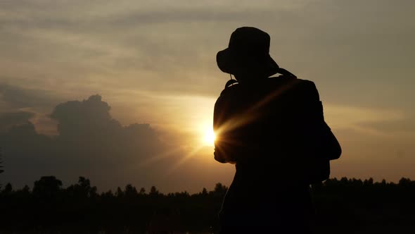 Silhouette of Woman are standing on the rock on the mountain looking to sunset. alt