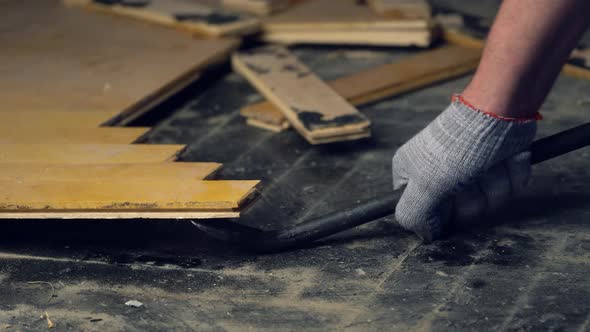 Worker Removes Old Parquet Using a Tire Iron Tool During a Flat Renovation alt