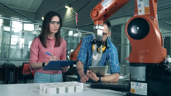 Robotic Arm Moves Cubes While Engineers Watch It. alt