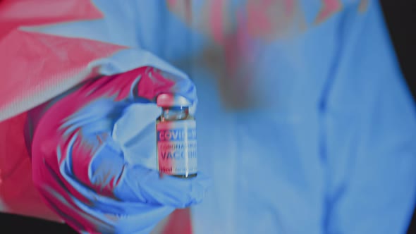 Close Up of the Doctors Hands Holding an Ampule with Vaccine in Emergency Light alt