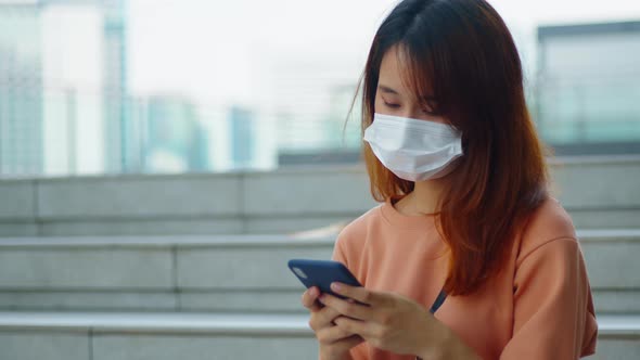 Young asian woman wearing medical mask hand holding phone and  using a smartphone