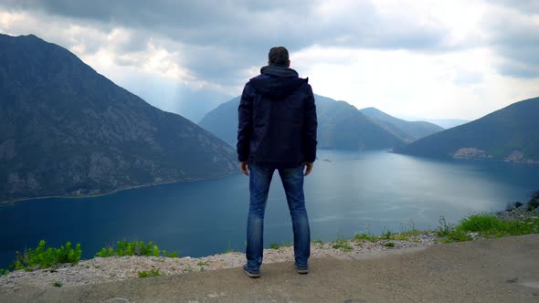Man Standing on Mountain Peak Enjoys Mindblowing Landscape alt