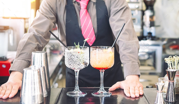 Young bartender making cocktails at bar counter - Barman serving drinks