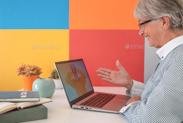 Elderly woman amused video chatting with friend by laptop laughing while she talks to a distant man