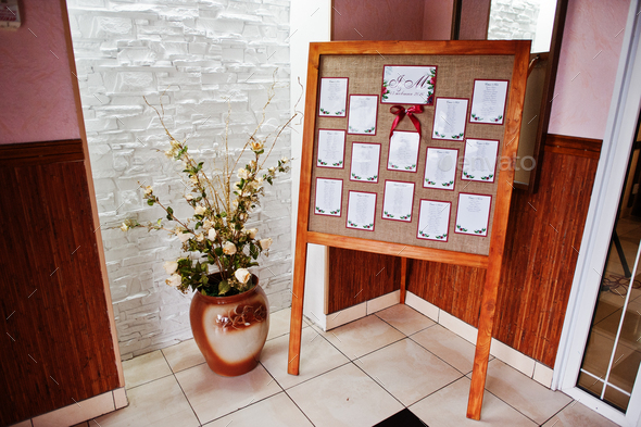 Wedding wooden board with guest list and table numbers on it.