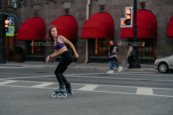 Slim sporty young woman uses rollerskates as mode of transportation in city enjoys favourite hobby. - Stock Photo - Images