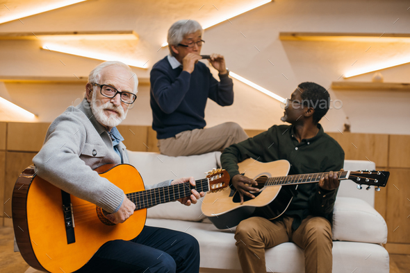 group of handsome senior friends playing music with guitars and harmonica