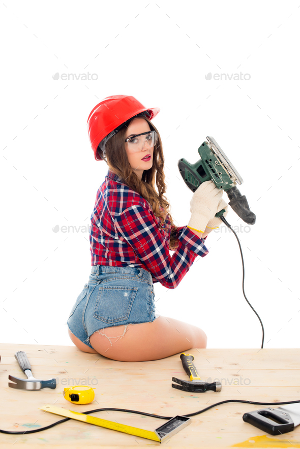 sexy girl posing with grind tool on wooden table with tools, isolated on white
