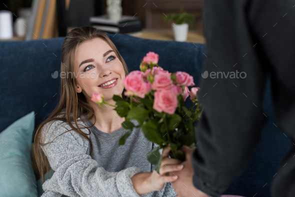cropped image of boyfriend presenting bouquet of roses to girlfriend on international womens day