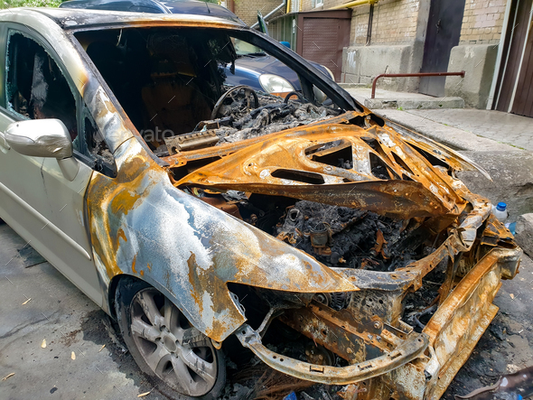 Closeup of burnt rusted car left on the city street destroyed by fire