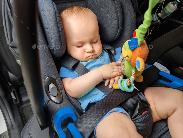 Portrait of cute little baby boy sleeping in car in the safety seat - Stock Photo - Images