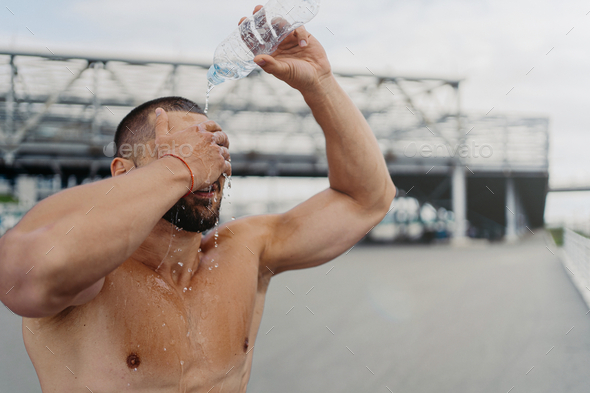 Sportsman splashes fresh cold water over head, tries to refresh after hard exercising outdoor.