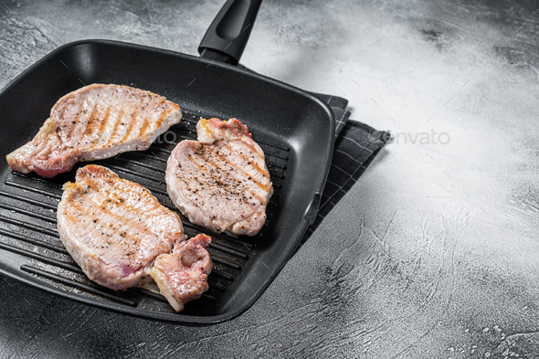 Fried on a grill skillet pork chop steaks. White background. Top view. Copy space