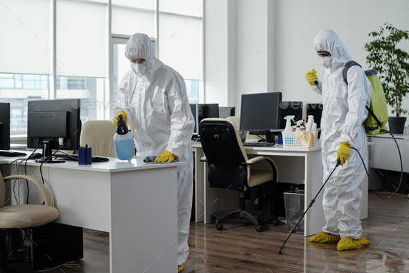 Two workers of disinfection service company working in openspace office