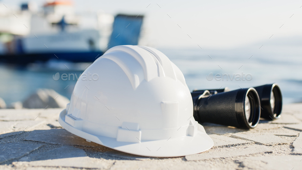White engineer helmet and binoculars in a naval port - Stock Photo - Images