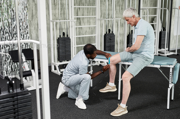 Rehabilitation Therapist Putting Taping on Knee