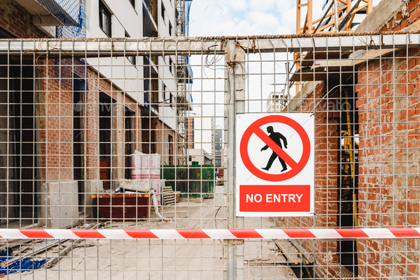 Closed access door to the construction site of a building, with a no-entry sign.