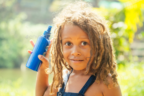 Mowgli indian boy with dreadlocks hair hiding holding mosquito spray
