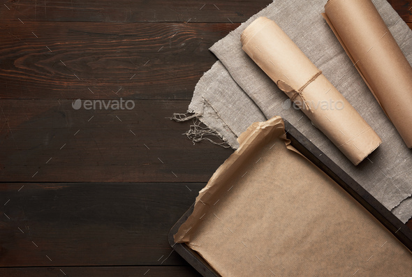 Empty rectangular metal pan covered with brown parchment paper and paper  rolls Stock Photo by ndanko
