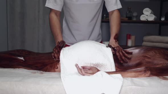 Closeup of Masseur Doing Massage with Chocolate Scrub alt