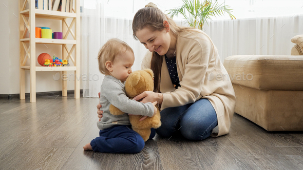 Mother and baby boy playing with teddy bear - Stock Photo - Images
