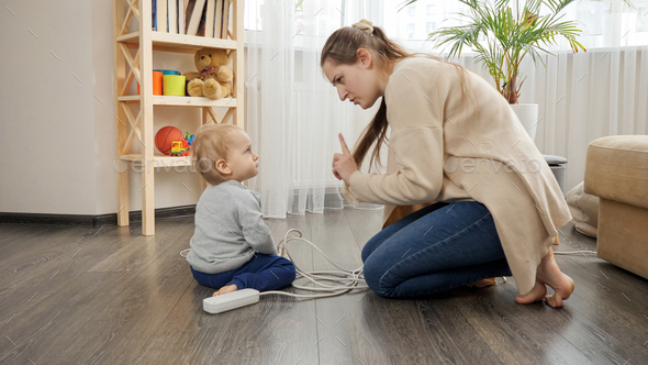 Young caring mother telling her baby son not to play with electricity - Stock Photo - Images