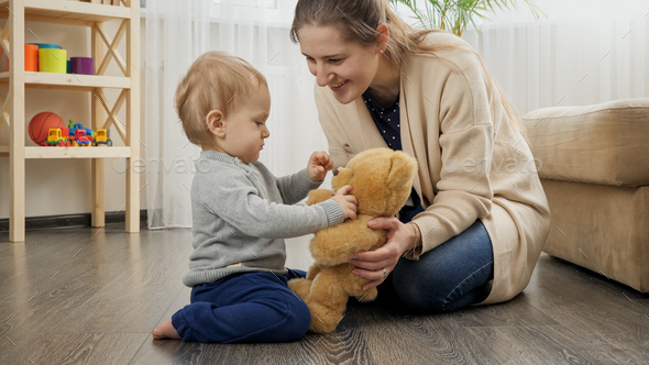 Happy smiling mother teaching her baby son and playing with teddy bear - Stock Photo - Images